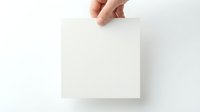 Hand holding blank white paper sheet against clean background for mockup and presentation purposes.