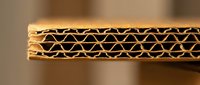 Corrugated cardboard cross-section showing internal fluted structure and layers. Brown packaging material with visible wave pattern for shipping and storage.