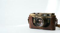 Vintage rangefinder camera with leather case on white background, classic photography equipment for retro design projects and nostalgic themes.