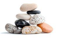 Stack of smooth pebbles and stones in different colors and textures on white background, balanced composition for spa, wellness, and meditation concepts.