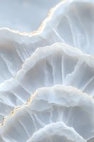 Ethereal white onyx mineral texture with translucent layers and golden veining creates an abstract natural pattern for luxury interior design backgrounds.