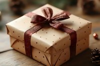 Kraft paper gift box with brown polka dots wrapped with shimmering burgundy ribbon bow on wooden surface, festive holiday present packaging for special occasions.