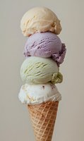 Stacked scoops of colorful ice cream flavors in waffle cone against neutral background, featuring vanilla, pistachio, berry and cream varieties for dessert menu.