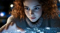 Young woman with curly red hair looking at glowing digital interface with floating holographic icons in futuristic technology concept for innovation and connectivity.