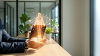 Business professional holding glowing lightbulb with innovation network connections in modern office workspace for creative thinking concepts.