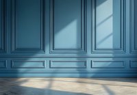 Classic blue wall paneling with geometric shadows cast from window light on empty room interior featuring herringbone wooden flooring and decorative molding.