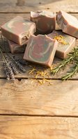 Handmade natural soap bars with swirled patterns on rustic wooden background with lavender and rosemary herbs for organic skincare and spa treatments.