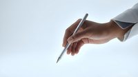 Professional hand holding silver pen ready to write on clean white background for business documentation and signing contracts.