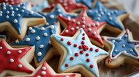 Star-shaped sugar cookies decorated in patriotic red, white and blue royal icing with polka dot details, arranged on wooden surface. Fresh baked holiday treats.