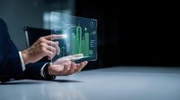 Businessman in suit holding transparent tablet displaying green financial growth charts and data analytics for investment and business strategy concepts.