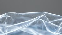 Transparent plastic wrap material with wrinkled texture and reflective surface creating abstract geometric patterns for packaging design applications.