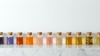 Assorted essential oils and liquid extracts in glass bottles with cork stoppers arranged in a row on marble surface, suitable for aromatherapy, wellness, and cosmetic product design.