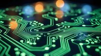 Circuit board with glowing green and blue pathways and orange bokeh lights, representing digital technology, data flow, and electronic connectivity for tech backgrounds.