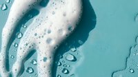 White foam soap bubbles on turquoise blue background with water droplets for skincare and hygiene products advertising and cosmetic packaging design.