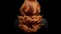 Stunning copper red wavy hair with glossy shine and voluminous curls cascading down back against dark background for beauty and haircare concepts.
