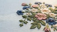 Colorful hand embroidered floral design with pink and blue flowers on white fabric showcasing traditional needlework craftsmanship for textile arts projects.