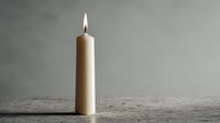 Burning beige candle with bright flame on rustic wooden surface against neutral background for relaxation and meditation concepts.