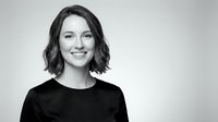 Professional young Caucasian businesswoman with wavy bob haircut smiling confidently in black top against neutral background for corporate branding.