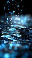 Magical blue bokeh lights and water drops creating ethereal atmosphere with blurred glowing particles floating above dark reflective surface at night.