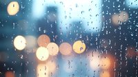 Raindrops on window glass create abstract pattern with defocused city lights in background creating atmospheric moody evening scene with bokeh effect.