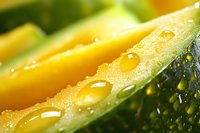 Fresh sliced cucumber with water droplets in extreme macro view showing detailed texture and natural moisture on green and yellow vegetable surface.