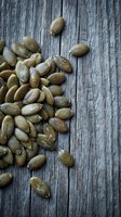 Raw pumpkin seeds scattered on rustic wooden background for healthy snacking and cooking ingredients.