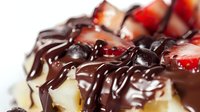 Decadent dessert slice with fresh strawberries, dark chocolate drizzle, and whipped cream on white plate, extreme close up macro food photography.
