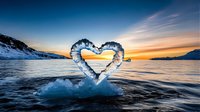 Heart-shaped ice formation floating on dark ocean water against dramatic sunset sky and snowy mountains, creating romantic winter landscape. Perfect for Valentine's Day designs.