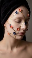 Young Caucasian woman with closed eyes, golden floral face art with blue and coral flowers, towel on head, creative beauty concept.