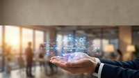 Businessman holding holographic digital network with connected icons floating above palm in modern office environment with warm lighting and blurred background.
