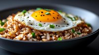 Fried rice with sunny side up egg topped with fresh herbs in dark bowl, Asian cuisine comfort food for restaurant menus and cooking blogs.