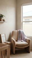 Cozy reading nook with beige armchair, lavender throw blanket, small wooden side table, framed artwork, potted plant on shelf, and bright window with natural light.