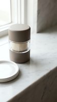 Minimalist cosmetic jar with beige cap on marble surface near window with natural light for skincare and beauty product packaging design.