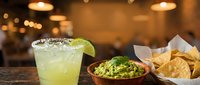 Refreshing margarita with lime and salt rim served at bar counter with guacamole dip and tortilla chips, perfect for restaurant, bar, or cocktail menu design.