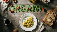 Organic vegetable omelette on rustic wooden table with basil leaves spelling organic, cherry tomatoes, coffee, and whole grain bread.