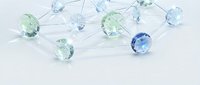 Network of connected blue and green crystal gems with silver lines on white background representing blockchain technology and digital connections.