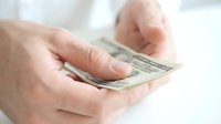 Male hands holding US dollar bills, counting or exchanging money in close-up. Suitable for finance, banking, wealth, and business concepts.