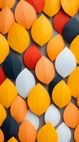Colorful paper leaves in autumn colors arranged in rows on gray background creating geometric pattern with orange, yellow, white and navy blue foliage.