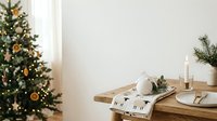 Minimalist holiday table setting with decorated evergreen tree, wooden furniture, white ceramic decor, candles, and natural seasonal styling for festive home interior design projects.