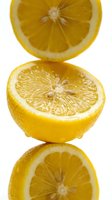 Fresh sliced lemon halves stacked vertically on white background with reflection, showcasing juicy citrus texture and vibrant yellow color.