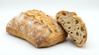 Artisan sourdough bread loaf with rustic crust and airy crumb texture, freshly baked bakery product isolated on white background for culinary designs.