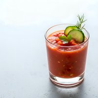 Fresh tomato bloody mary cocktail with cucumber garnish and rosemary sprig in glass on gray surface for brunch menu and bar service.