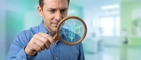 Caucasian businessman examining digital data through magnifying glass in modern office environment for business analysis and research purposes.