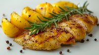 Grilled chicken breast sliced and served with roasted yellow potatoes, fresh rosemary sprigs and scattered peppercorns on light background for menu design.