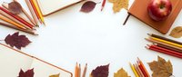 Autumn school supplies frame with colorful pencils, notebooks, red apple and fallen leaves on white background for educational design projects.