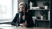 Professional middle-aged Caucasian woman with blonde hair speaking into podcast microphone in modern home office studio setup for broadcasting content creation.