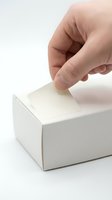 Close-up of caucasian hand inserting blank ballot into white box for voting, election, survey, or polling concept on white background.