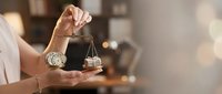 Professional woman holding golden scales of justice in modern office setting representing legal services and law firm consultation.