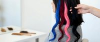 Stylist holding long black hair with vibrant blue and pink colored extensions, showcasing hair coloring techniques and salon services for beauty and fashion design projects.