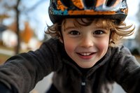 Happy young boy wearing colorful winter hat smiling at camera outdoors during cold season. Child portrait with warm clothing and joyful expression.